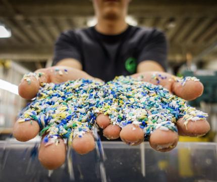 outstretched hands holding hundreds of small pieces of blue, yellow and white plastic pieces