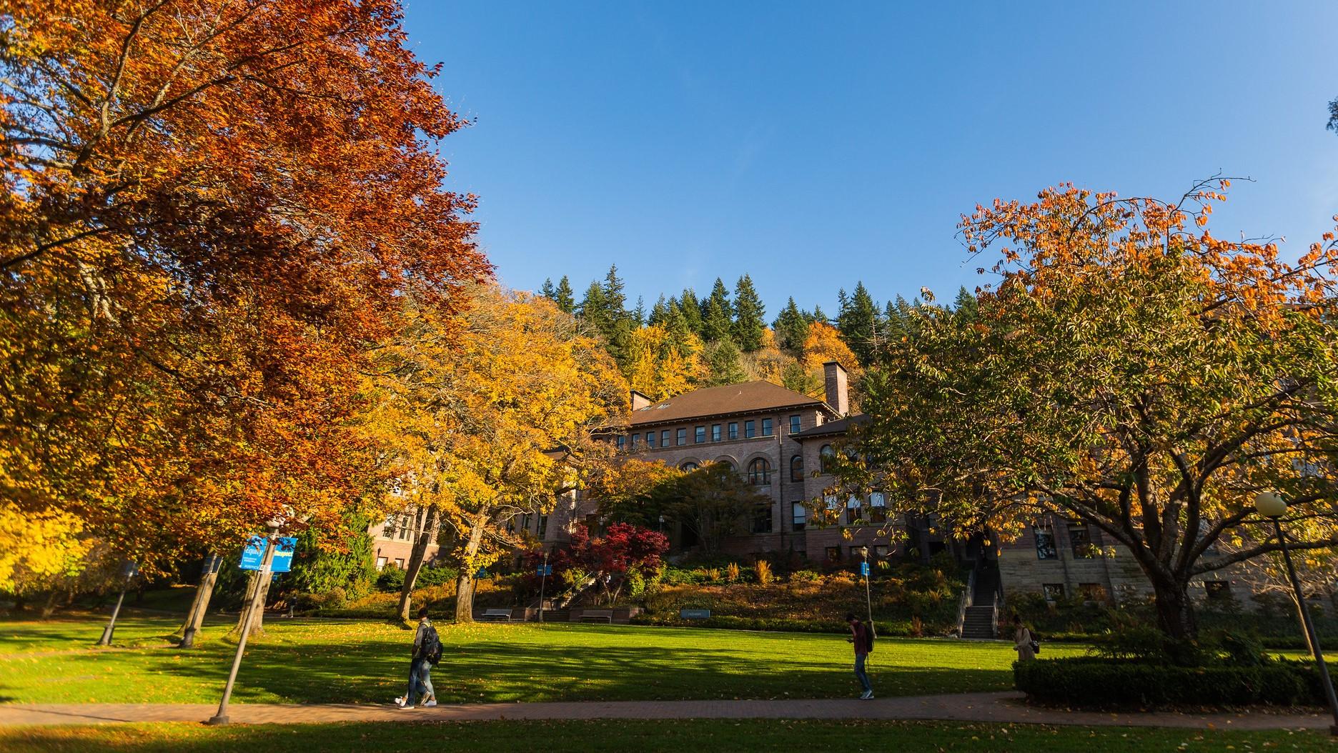 Old Main surrounded by trees with yellow and orange leaves in fall