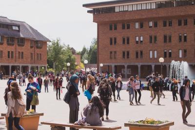 Students interacting in Red Square with Fisher Fountain and Bond Hall in the background.